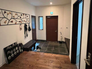 This charming entryway boasts a unique metal wall art piece, a convenient bench for seating, and ample storage for shoes and outerwear.