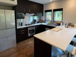 This modern kitchen boasts sleek dark brown cabinetry, stainless steel appliances, and a spacious island with seating.