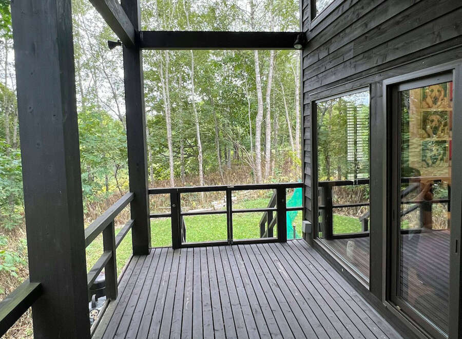 This home boasts a spacious deck overlooking a lush green landscape, perfect for outdoor relaxation and entertaining.
