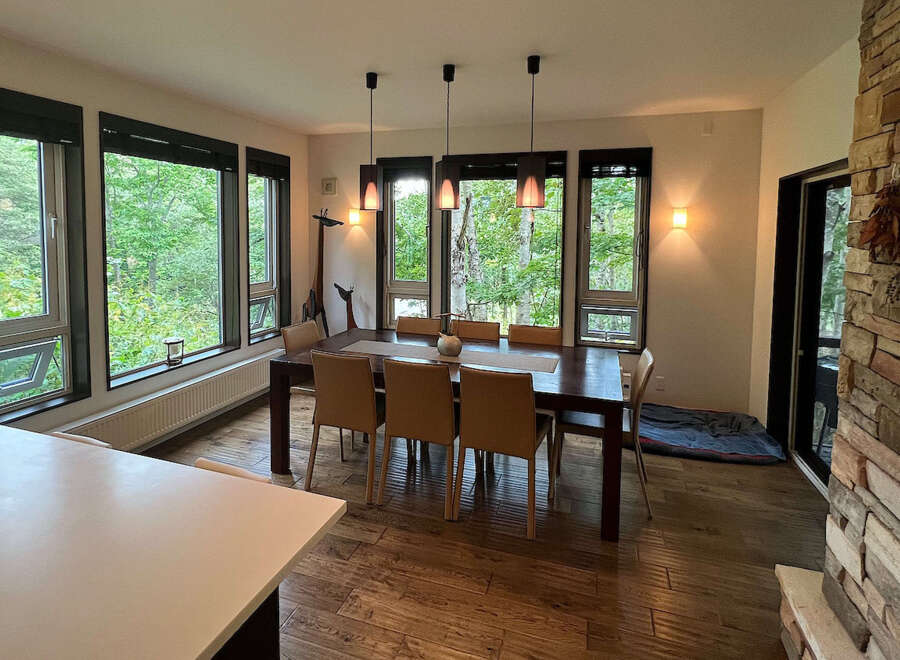 This stunning property boasts a spacious dining area with large windows offering breathtaking views of the surrounding forest.
