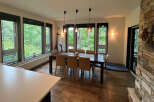 This stunning property boasts a spacious dining area with large windows offering breathtaking views of the surrounding forest.