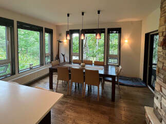 This stunning property boasts a spacious dining area with large windows offering breathtaking views of the surrounding forest.