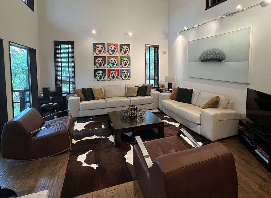 This stunning living room boasts a spacious and open floor plan, highlighted by large windows offering abundant natural light and views of the surrounding landscape.