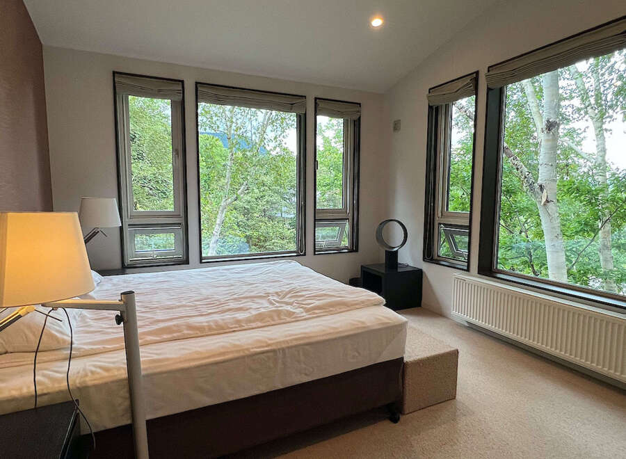 Wake up to breathtaking views of lush greenery from this bedroom's expansive windows.