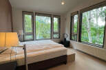 Wake up to breathtaking views of lush greenery from this bedroom's expansive windows.