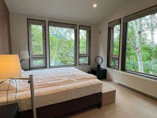 Wake up to breathtaking views of lush greenery from this bedroom's expansive windows.