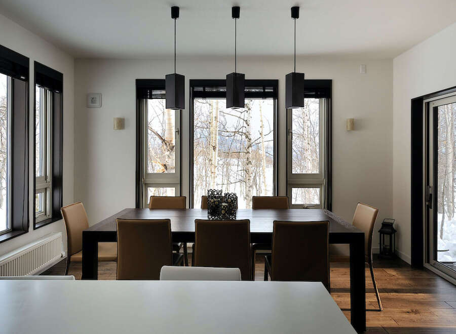 Modern dining room with large windows offering stunning views of a snowy landscape.