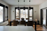 Modern dining room with large windows offering stunning views of a snowy landscape.