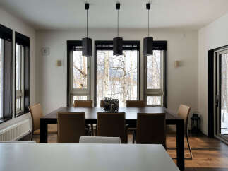 Modern dining room with large windows offering stunning views of a snowy landscape.