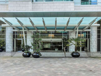 This stunning building boasts a grand entrance with a modern glass canopy, creating a welcoming and elegant atmosphere.