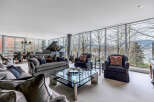 This luxurious living space boasts floor-to-ceiling windows offering breathtaking views of the natural landscape, creating a bright and airy atmosphere.