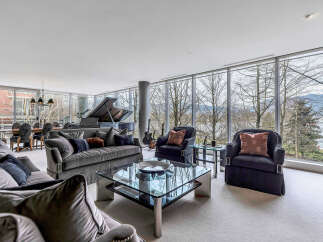 This luxurious living space boasts floor-to-ceiling windows offering breathtaking views of the natural landscape, creating a bright and airy atmosphere.