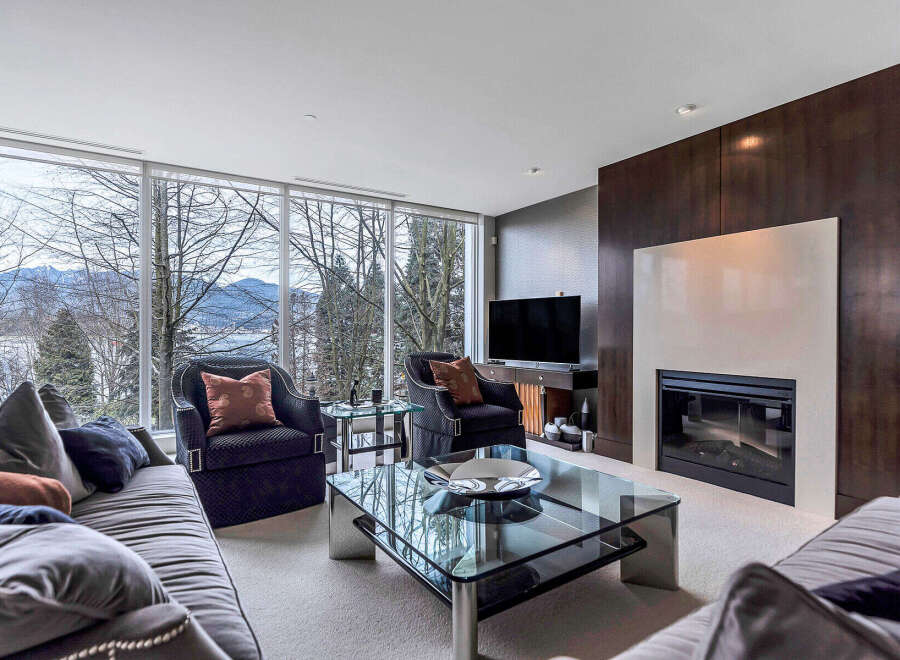 This luxurious living room boasts stunning views of mountains and water through expansive windows, creating a serene and inviting atmosphere.