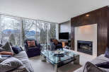 This luxurious living room boasts stunning views of mountains and water through expansive windows, creating a serene and inviting atmosphere.