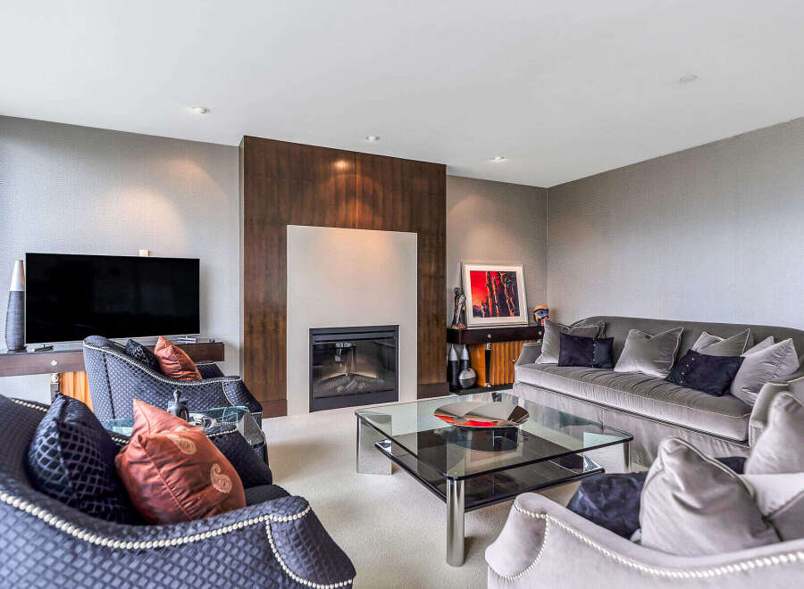 This luxurious living room boasts a stunning fireplace with a modern design, complemented by plush velvet sofas and armchairs.