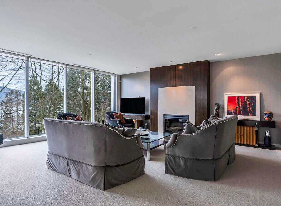This luxurious living room boasts floor-to-ceiling windows offering breathtaking views, creating a bright and airy atmosphere.