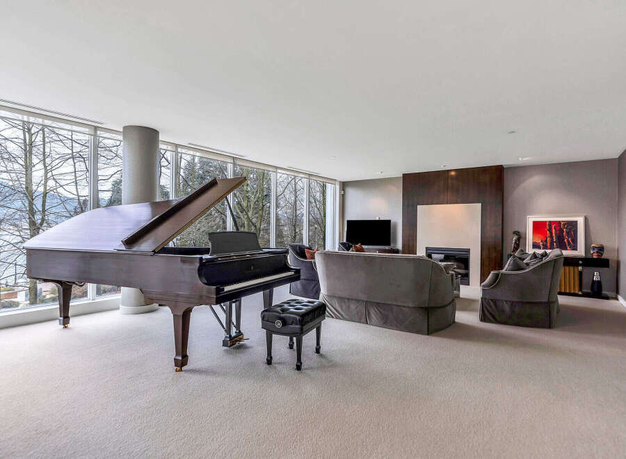 This luxurious living room boasts floor-to-ceiling windows offering breathtaking views, complemented by a grand piano and plush seating.