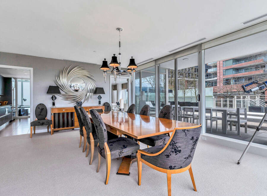 This luxurious condo boasts a spacious dining area with a large wooden table, surrounded by elegant chairs and a stunning mirror.