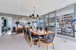 This luxurious condo boasts a spacious dining area with a large wooden table, surrounded by elegant chairs and a stunning mirror.