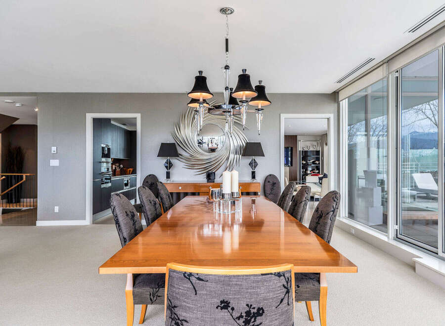 This luxurious dining room boasts a large, polished wooden table surrounded by elegant chairs, illuminated by a stunning chandelier.