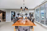 This luxurious dining room boasts a large, polished wooden table surrounded by elegant chairs, illuminated by a stunning chandelier.