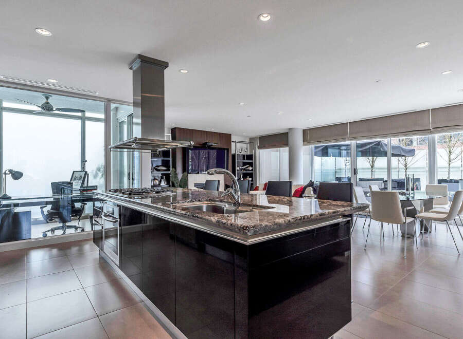 This luxurious condo boasts a stunning modern kitchen with high-end finishes, including granite countertops and sleek black cabinetry.