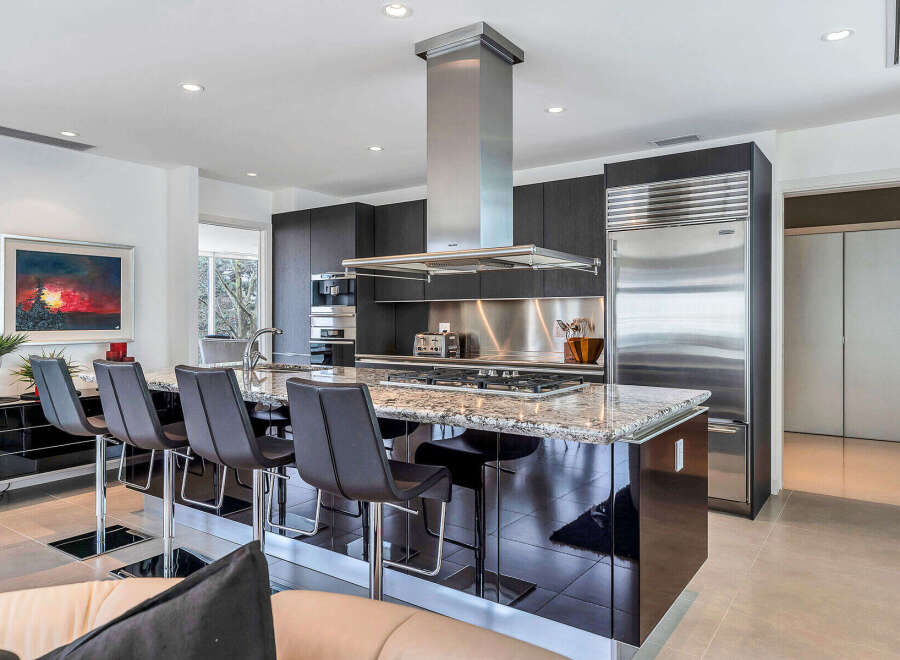 This stunning kitchen boasts a large island with seating, sleek dark cabinetry, and high-end stainless steel appliances.