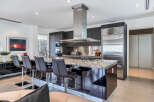 This stunning kitchen boasts a large island with seating, sleek dark cabinetry, and high-end stainless steel appliances.
