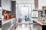 This stunning kitchen boasts sleek, dark gray cabinetry with stainless steel accents, complemented by granite countertops and high-end appliances.