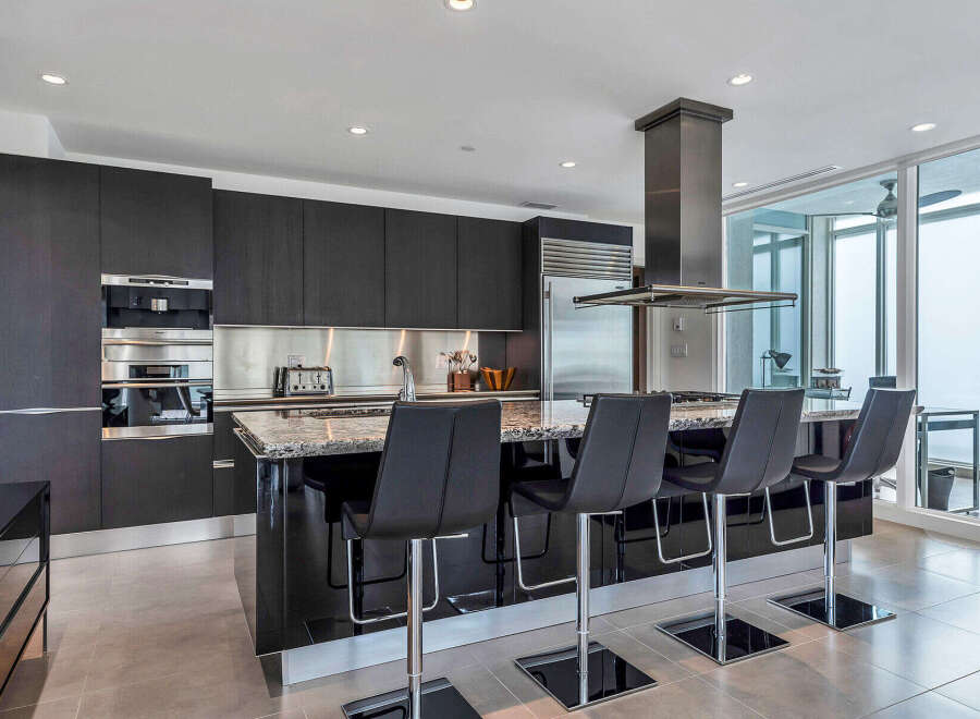 This stunning kitchen boasts sleek dark cabinetry, stainless steel appliances, and granite countertops.