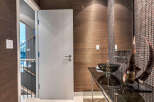 This modern powder room boasts a sleek glass vanity with a unique vessel sink, complemented by dark brown mosaic tile and textured wallpaper.