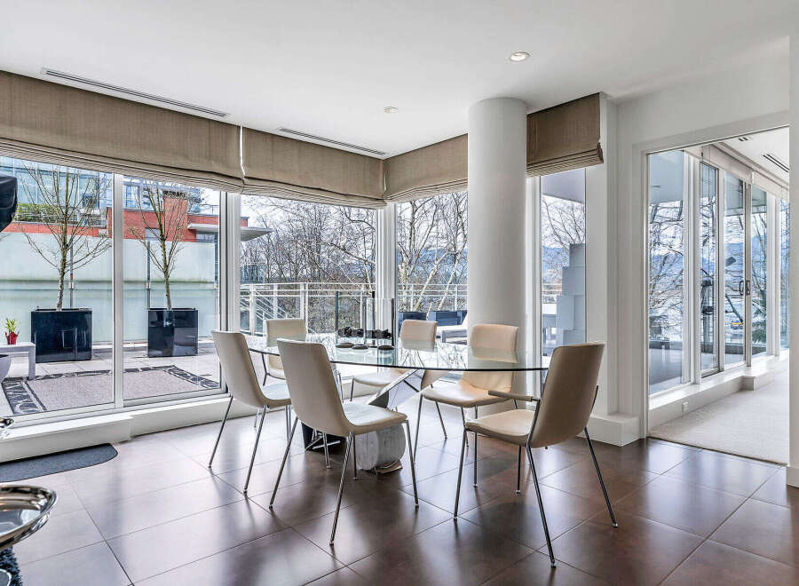 This luxurious condo boasts a spacious dining area with floor-to-ceiling windows offering breathtaking views.