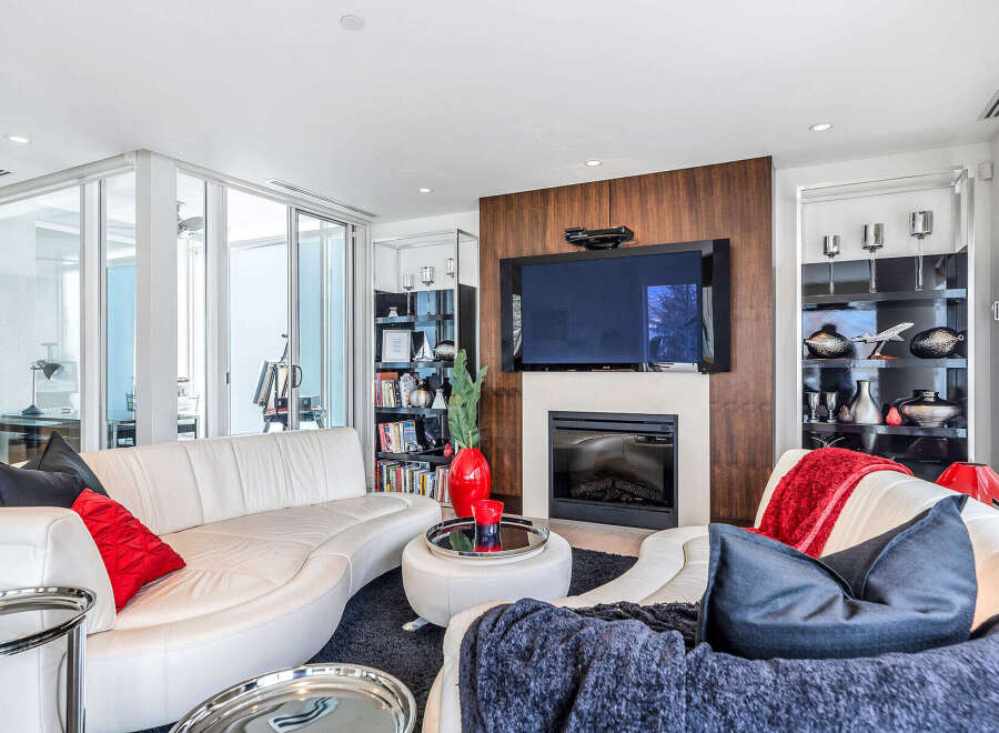This luxurious living room boasts a stunning modern fireplace, large flat-screen TV, and floor-to-ceiling windows offering ample natural light.