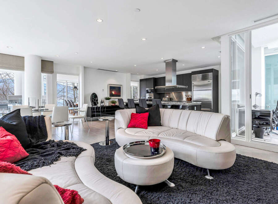 This luxurious condo boasts an open-concept living area with floor-to-ceiling windows offering stunning views, seamlessly connecting to a modern kitchen with stainless steel appliances.