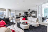 This luxurious condo boasts an open-concept living area with floor-to-ceiling windows offering stunning views, seamlessly connecting to a modern kitchen with stainless steel appliances.