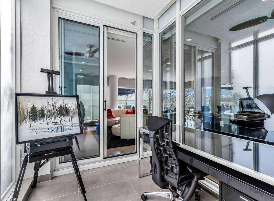This stunning condo boasts a sun-drenched balcony office with floor-to-ceiling windows offering breathtaking views.