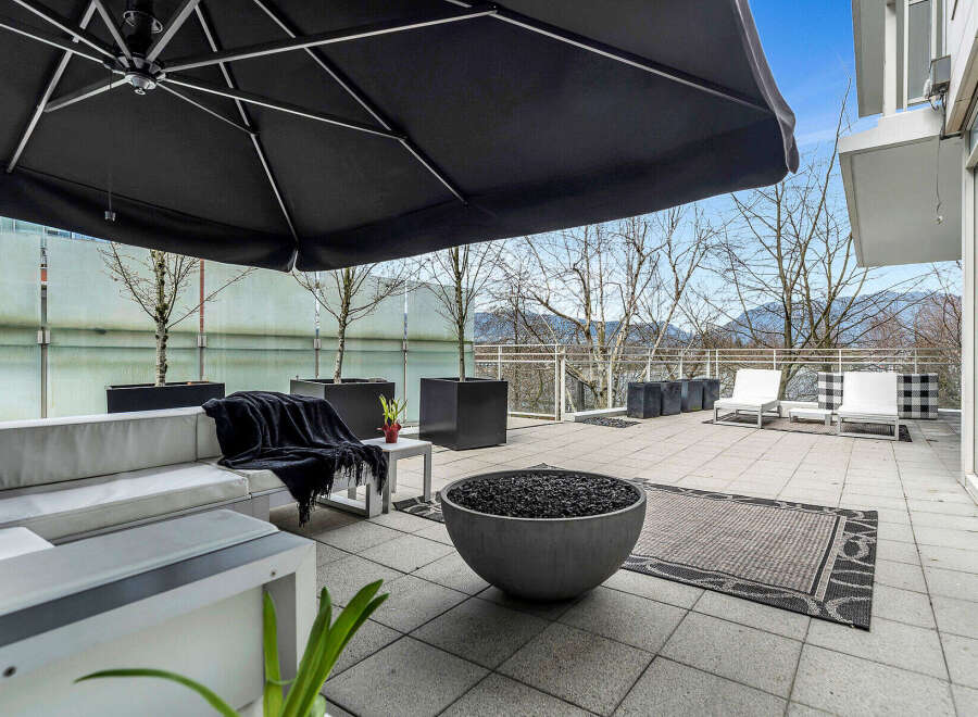 This luxurious condo boasts a spacious outdoor patio perfect for entertaining, complete with comfortable seating, a fire pit, and a large umbrella for shade.