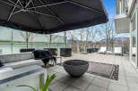 This luxurious condo boasts a spacious outdoor patio perfect for entertaining, complete with comfortable seating, a fire pit, and a large umbrella for shade.