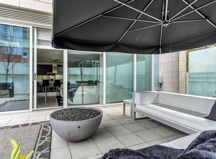 This modern outdoor patio features a sleek, white sectional sofa perfect for relaxing, and a fire pit for ambiance.