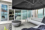 This modern outdoor patio features a sleek, white sectional sofa perfect for relaxing, and a fire pit for ambiance.