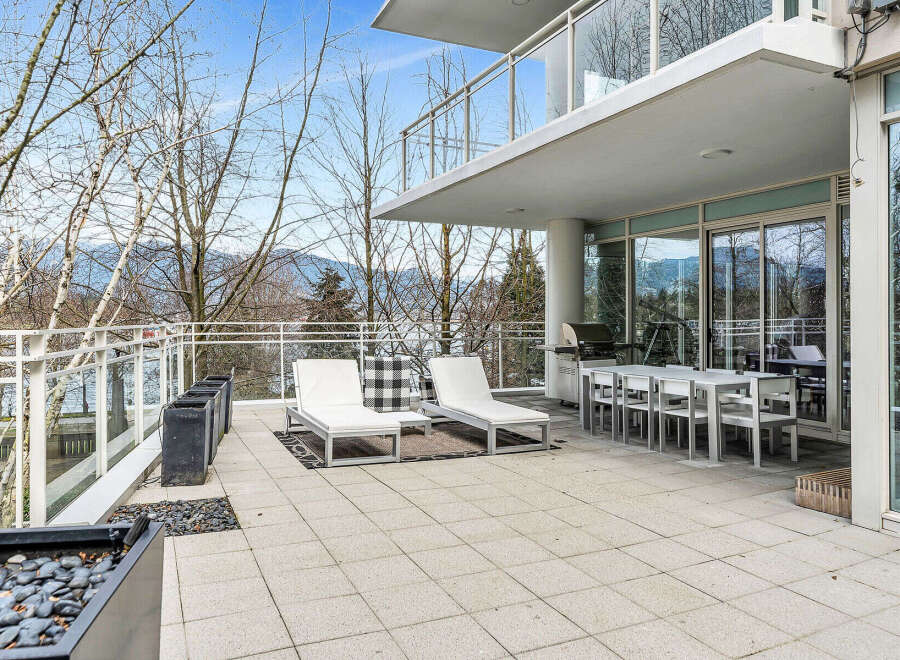 This luxurious condo boasts a spacious outdoor patio perfect for entertaining, complete with comfortable lounge chairs and a dining area.