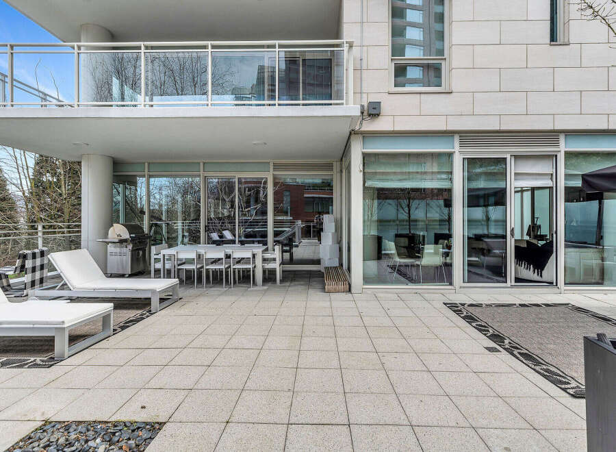 This luxurious condo boasts a spacious outdoor patio perfect for entertaining, complete with a built-in BBQ and comfortable lounge furniture.