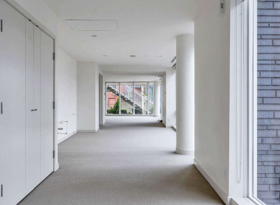 This modern, bright hallway boasts sleek white walls and flooring, creating an airy and spacious feel.