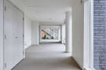 This modern, bright hallway boasts sleek white walls and flooring, creating an airy and spacious feel.