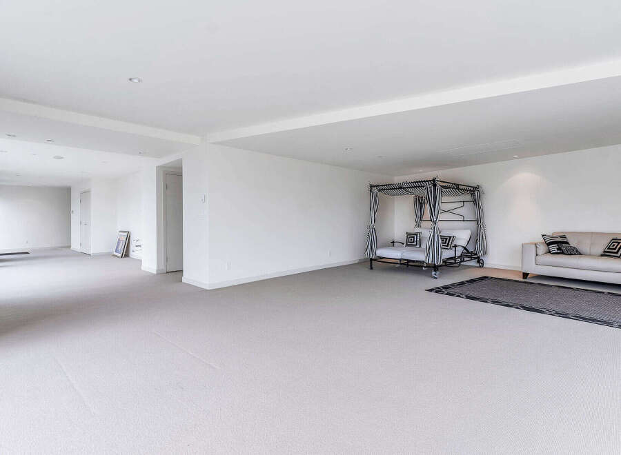 This spacious room boasts high ceilings, plush carpeting, and an abundance of natural light, creating a bright and airy atmosphere.