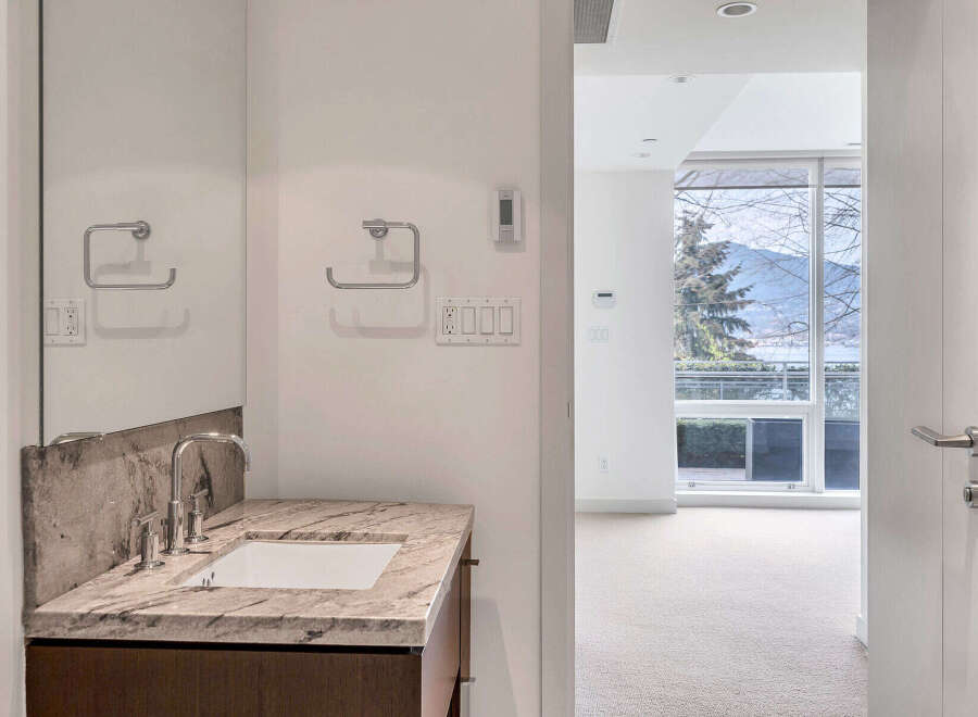 This modern bathroom boasts a sleek granite countertop vanity with a contemporary sink and faucet.