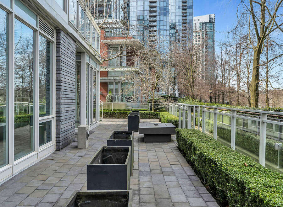 This modern condo boasts a private patio perfect for outdoor relaxation, featuring a sleek stone design and built-in planters.