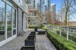 This modern condo boasts a private patio perfect for outdoor relaxation, featuring a sleek stone design and built-in planters.