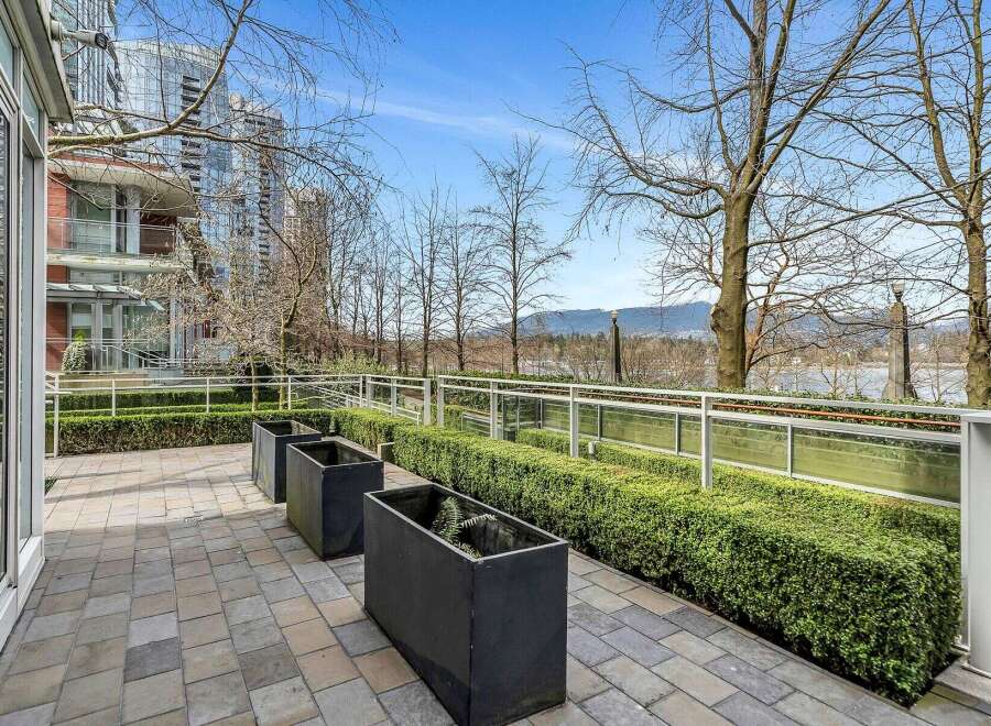 This stunning property boasts a private patio perfect for outdoor relaxation, complete with modern planters and a meticulously landscaped hedge offering both privacy and visual appeal.