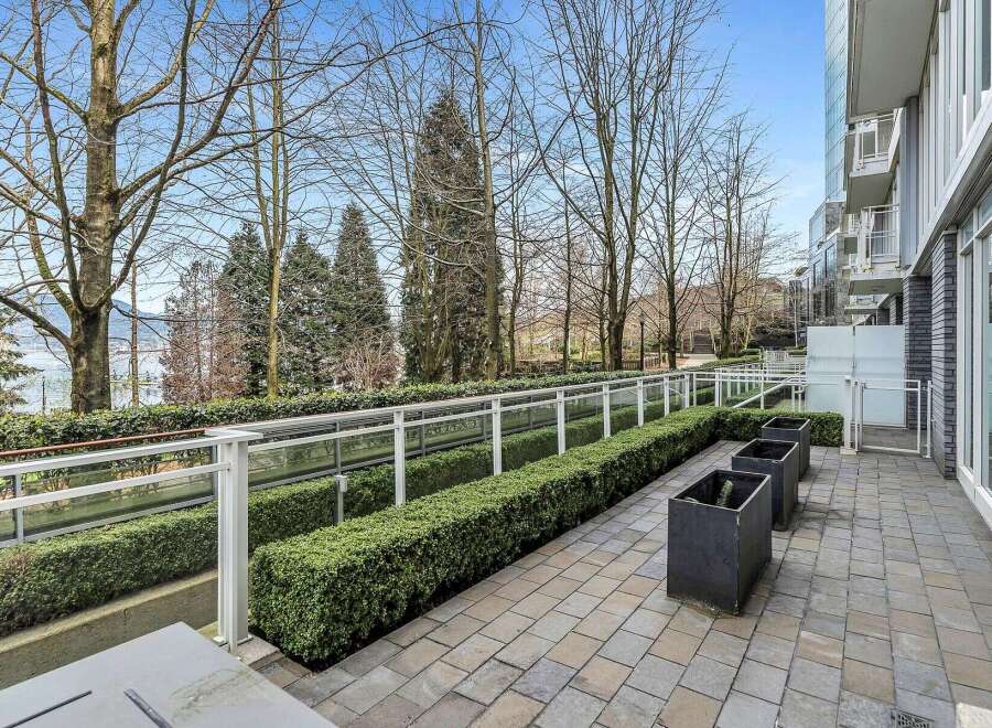 This stunning property boasts a private patio perfect for outdoor relaxation, complete with meticulously landscaped hedges and modern planters.
